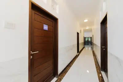a hallway with wooden doors and white walls at RedDoorz at Lotus House Seminyak in Seminyak
