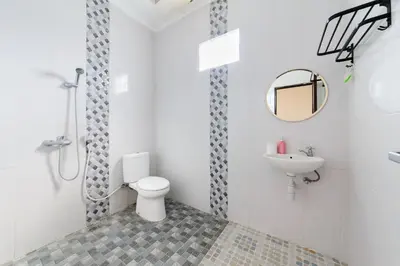 a white bathroom with a toilet and a sink at RedDoorz at Lotus House Seminyak in Seminyak