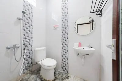a white bathroom with a toilet and a sink at RedDoorz at Lotus House Seminyak in Seminyak