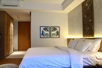 a bedroom with a white bed with two pictures on the wall at Cozy Minimalist Apartment Lavaya N511 in Nusa Dua