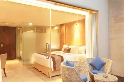 a hotel room with a bed and two chairs at de Vins Sky Hotel Seminyak in Seminyak