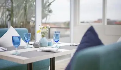 a table with blue glasses and a blue couch at de Vins Sky Hotel Seminyak in Seminyak