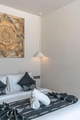 a bed with pillows and a painting on the wall at Berawa Breeze - Chic 4BR Beachside Oasis with Sauna in Canggu