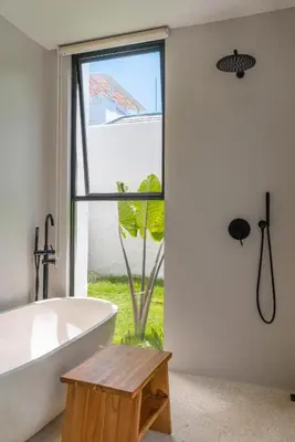 a bathroom with a tub and a large window at Berawa Breeze - Chic 4BR Beachside Oasis with Sauna in Canggu