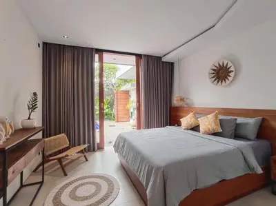 a bedroom with a bed and a table and a window at Cosy Haven 2 BR Villa in Umalas in Canggu