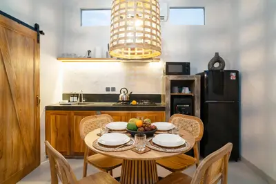 a kitchen with a table and chairs and a black refrigerator at Alaya Homes C - Elegant Japandi Loft Suite in Seminyak in Seminyak