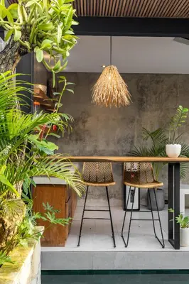 a table and chairs in a room with plants at 10 mins to beach - BRAND NEW 1 BD w/Pool + Netflix in Canggu