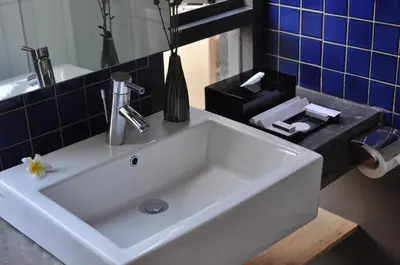 a white sink in a bathroom with blue tiles at Liberta Hotel Jimbaran in Jimbaran