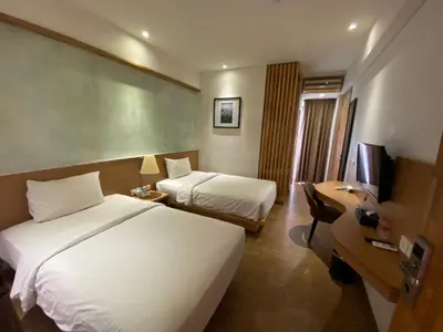a hotel room with two beds and a desk at Liberta Hotel Jimbaran in Jimbaran