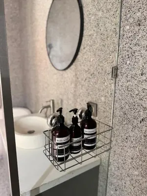 a bathroom with three shampoo bottles on a shelf in front of a mirror at Villa de Mer Bali in Legian