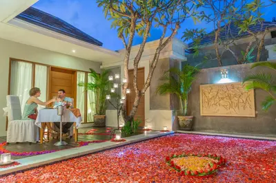 a man and woman sitting at a table in a room filled with red flowers at The Light Exclusive Villas and SPA in Seminyak