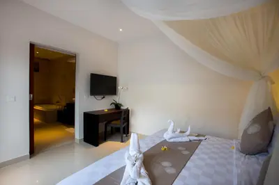 a bedroom with a bed and a room with a television at The Light Exclusive Villas and SPA in Seminyak