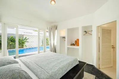 a white bedroom with a large bed and a balcony at LaLeBay Villa Seminyak in Seminyak