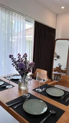 a table with plates and glasses and a vase of flowers at 2 bedroom villa in Umalas in Kerobokan
