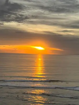 a sunset over the ocean with people in the water at Milavila in Seminyak