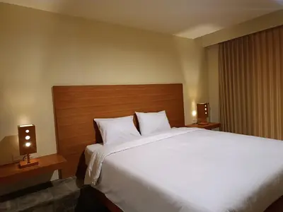 a bedroom with a large white bed with two lamps at Kuta Living by Kamara in Kuta