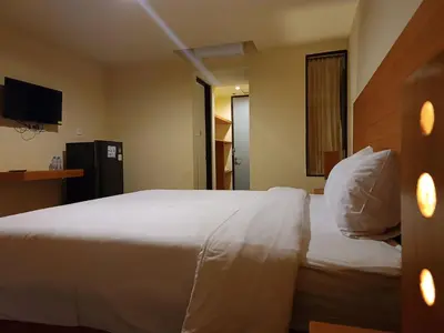 a hotel room with a white bed and a television at Kuta Living by Kamara in Kuta