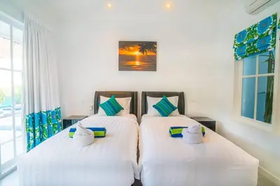 two beds in a bedroom with white sheets and towels at Villa Ley Charming 2 Bedroom Villa Seminyak Private Pool in Seminyak