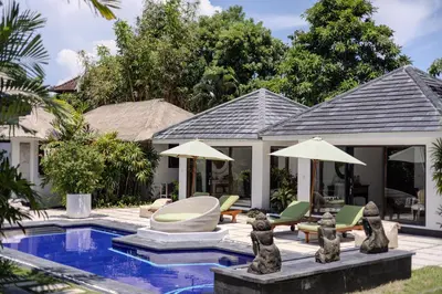 a house with a swimming pool with chairs and umbrellas at Villa Arev in Kerobokan