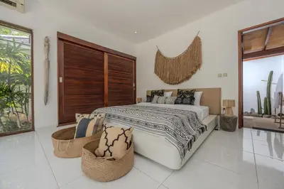 a bedroom with a large bed and two wicker chairs at Villa Arev in Kerobokan