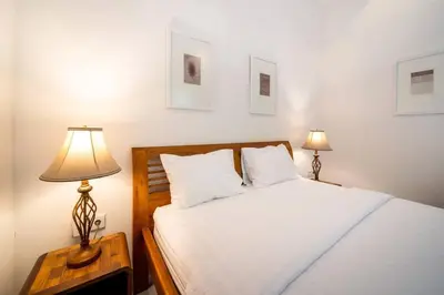 a bedroom with a white bed and two lamps at Villa Banua 3 Seminyak in Seminyak