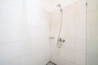 a white tiled shower with a shower head at Villa Banua 3 Seminyak in Seminyak