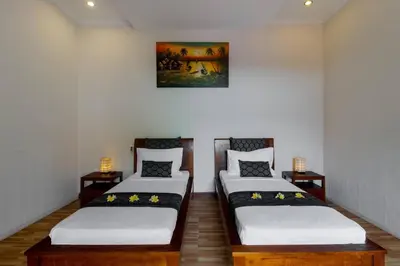a room with two beds and a painting on the wall at Villa Tranquil Holiday Villa in Seminyak