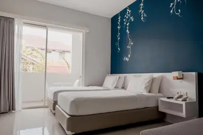 a bedroom with two beds and a blue wall at Cozy Stay Bali by ARM Hospitality in Seminyak