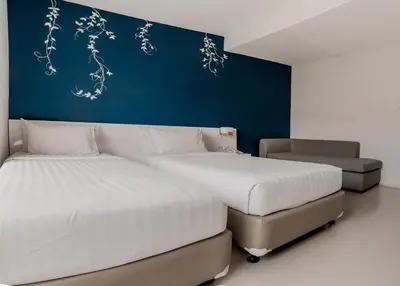 a bedroom with two beds and a blue wall at Cozy Stay Bali by ARM Hospitality in Seminyak