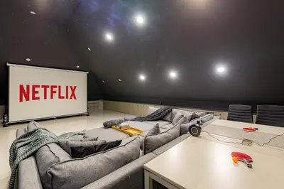 a theatre with couches and a screen with a netflix sign at Beautiful Penthouse w/ incredible views, pool, & cinema room! in Canggu