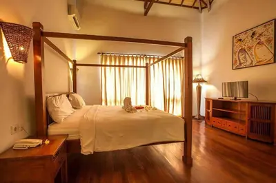 a bedroom with a canopy bed and a wooden floor at Clasic Private Pool Villa in Seminyak in Seminyak
