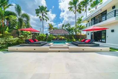 a pool in the backyard of a house with red umbrellas at Exquisite 4BD Luxury Villa in the Heart of Berawa in Canggu