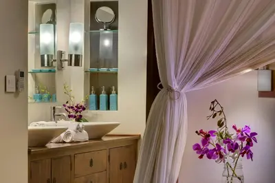 a bathroom with a sink and a curtain with purple flowers at LataLiana Seminyak in Seminyak