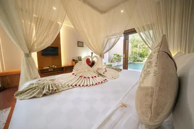 a bedroom with a large white bed with curtains at The Kasih Villas & Spa in Seminyak