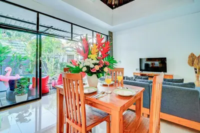a dining room with a table with a vase of flowers at Villa O'Anne in Seminyak