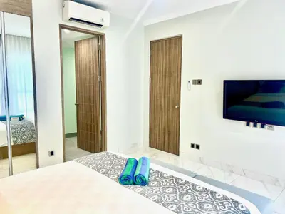 a bedroom with a bed with blue flip flops on a rug at The Bay Sunflower Apartment in Nusa Dua