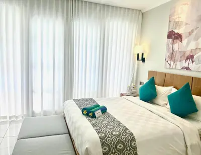 a bedroom with a large bed with blue pillows at The Bay Sunflower Apartment in Nusa Dua
