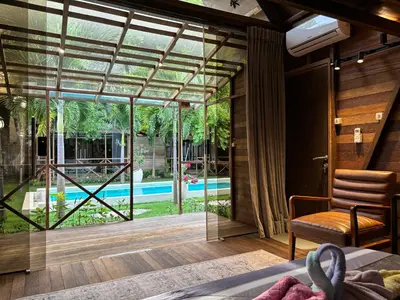 a bedroom with a view of a pool through a glass door at Bali Cozy Bungalows, Nusa Dua Benoa in Nusa Dua
