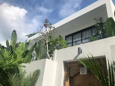 a white house with a wooden door and plants at Two-Bedroom Pool Villa at Anwa Residences in Canggu