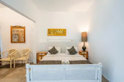 a bedroom with a white bed and a table and chairs at 5 Bedroom Villa Etnik in Seminyak with Big Garden and Private Pool in Seminyak