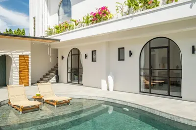 a house with a swimming pool and two chairs at Mysa Boutique Hotel in Seminyak