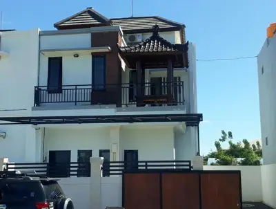 a white house with a balcony on top of it at Chandra's House in Denpasar