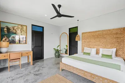 a bedroom with a bed and a desk at Abu Villa by Betterplace in Canggu