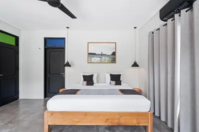 a bedroom with a large white bed with black pillows at Abu Villa by Betterplace in Canggu