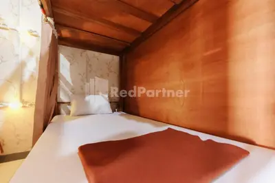 a small bedroom with a white bed with a wooden ceiling at Shooting Star Hostel Kuta RedPartner - mixed dormitory in Legian