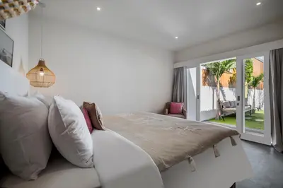 a white bedroom with a bed and a balcony at Villa Makena by Alfred in Bali in Seminyak