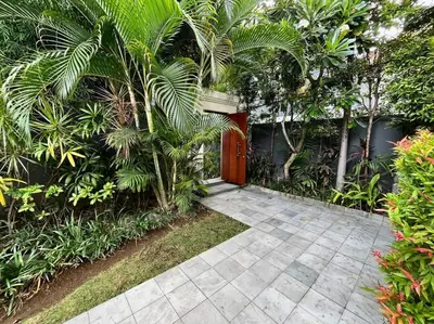 a pathway with a red door and palm trees at Villa Plawa in Seminyak