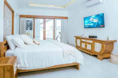 a bedroom with a large white bed and a desk at Villa Amil Seminyak in Seminyak