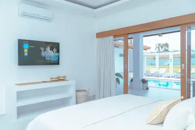 a bedroom with a bed with a tv on the wall at Villa Amil Seminyak in Seminyak
