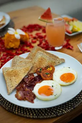 a plate of eggs and toast and a glass of orange juice at Villa Kelolyne in Seminyak